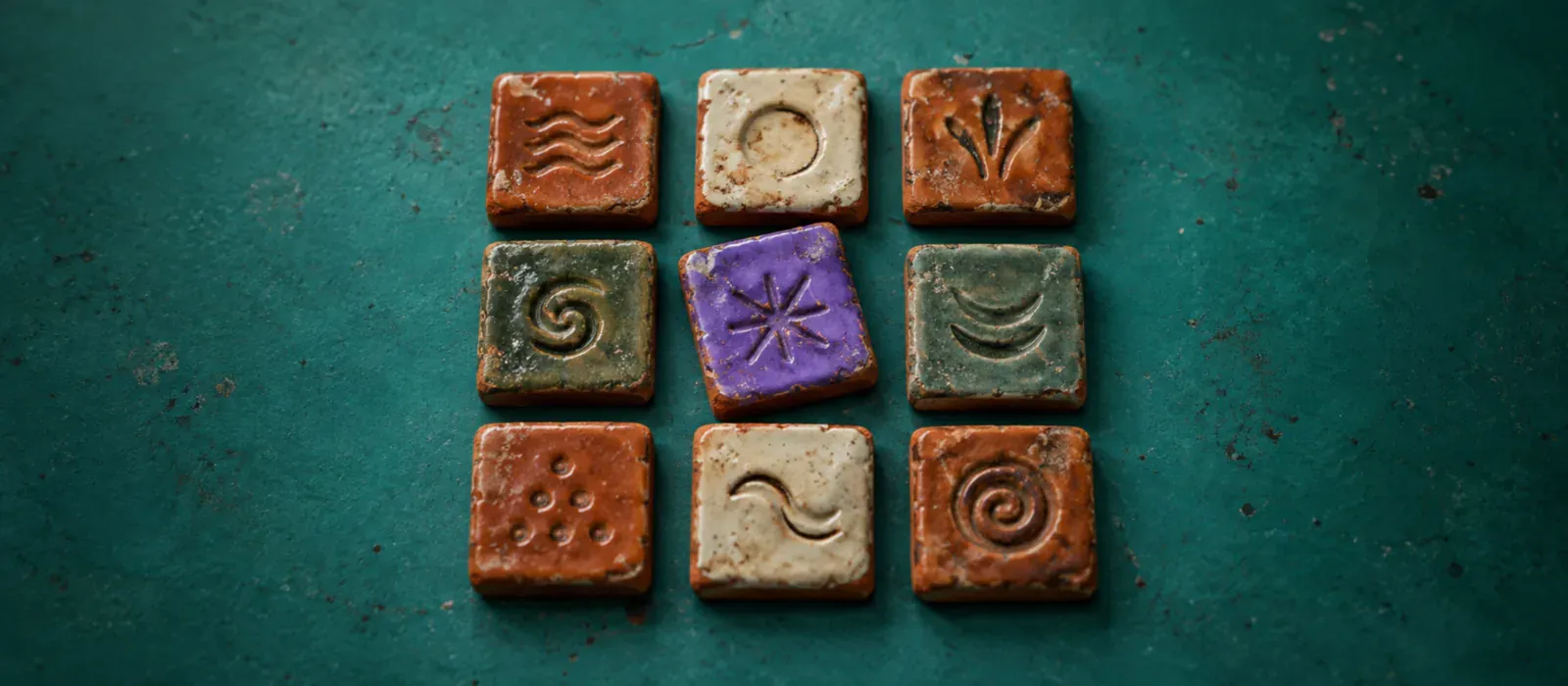 Nine small glazed terracotta tiles in a grid on a teal ground, each stamped with a different illegible mark, one glazed violet and set slightly out of line.